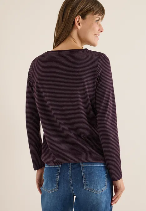 Frau mit gestreiftem Langarmshirt und blauer Jeans von hinten.